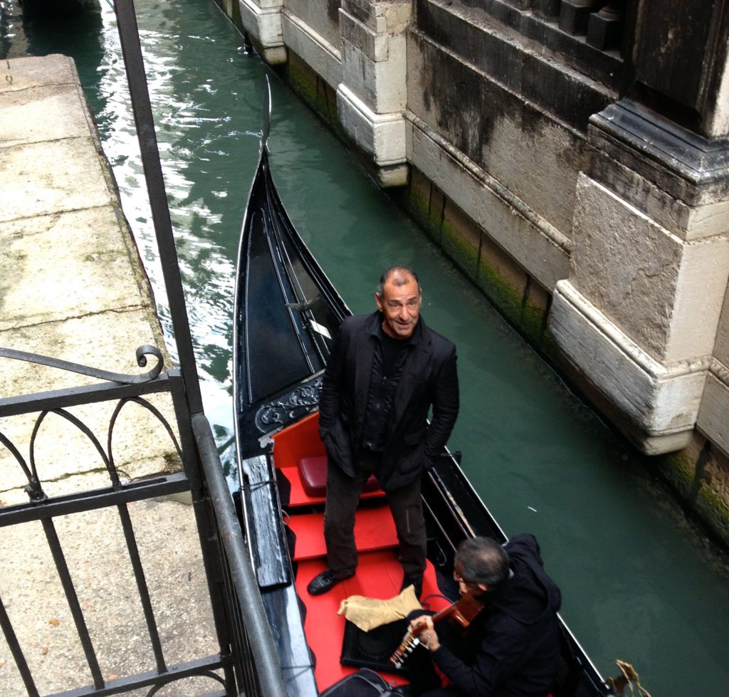 Venice with teens: singer and gondola pass bridge. Copyright©2015 reserved to photographer. Contact mapandfamily.com