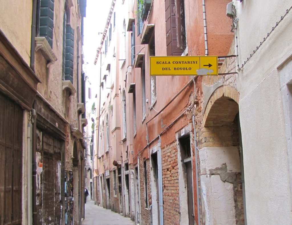 Venice with teens: yellow sign on pink wall. Copyright©2015 reserved to photographer. Contact mapandfamily.com