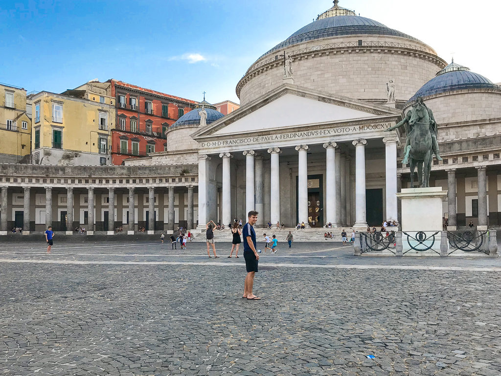 Boy trying to walk in a straight line across Piazza Plebescito Naples