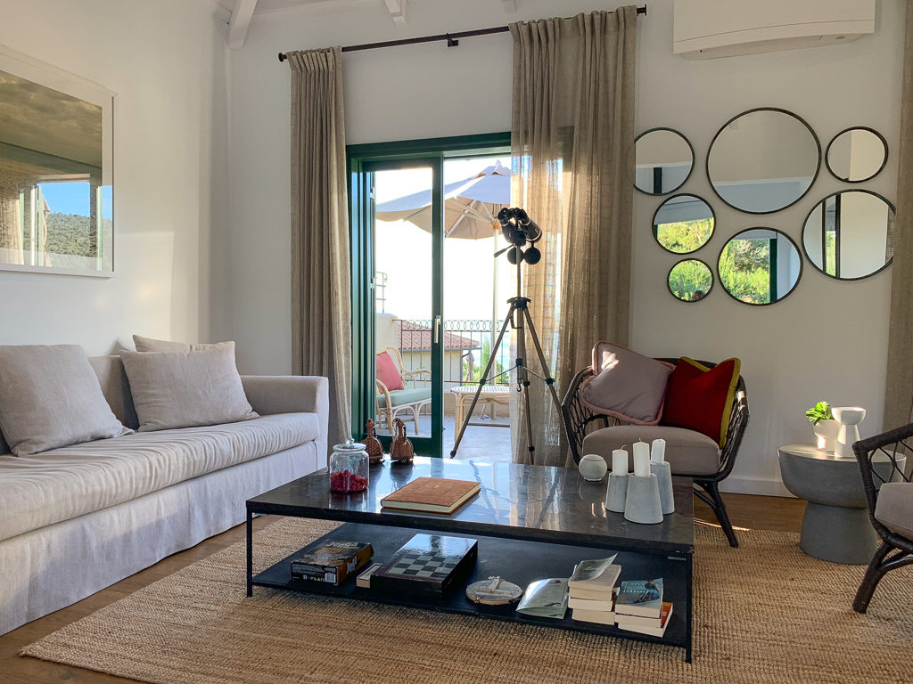 Luxury villas Kefalonia. Living area of villa showing seating, binoculars on a stand and doors onto the balcony. Copyright ©2020 mapandfamily.com