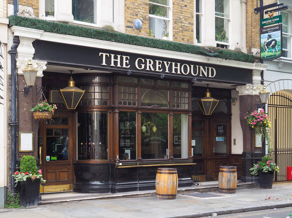 The exterior of The Greyhound pub near the Royal Albert Hall, has lanterns over the entrances and a broad bay window. Copyright@2023 mapandfamily.com