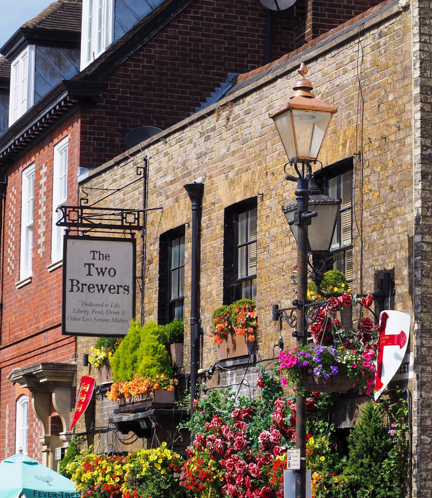 Exterior of old pub in Windsor with flower boxes, and old iron street lamp and hanging sign. Copyright@2023 mapandfamily.com 