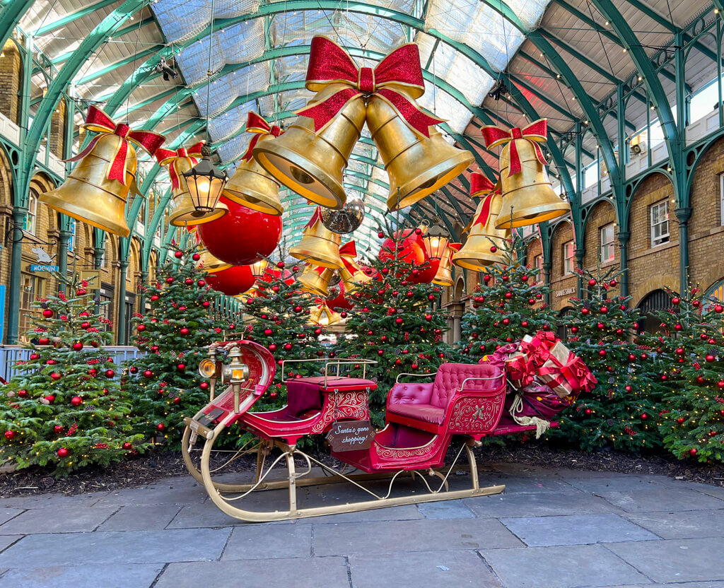 Antique red sleigh under bell decorations in market hall. Copyright@2024 mapandfamily.com