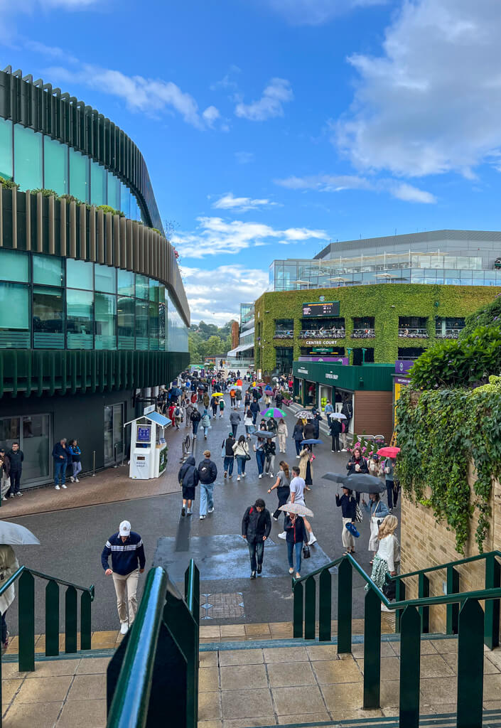 People carrying umbrellas walking between courts at Wimbledon tennis.Copyright@2025 NancyRoberts