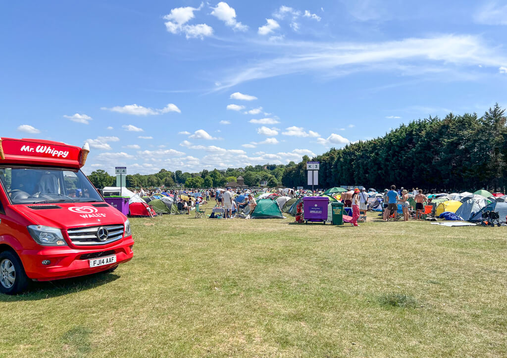 Wimbledon Queue 2025, the Sunday before the first day of play. A red Mr Whippy van in foreground and rows of tents and people under blue sky. Copyright@2025NancyRoberts